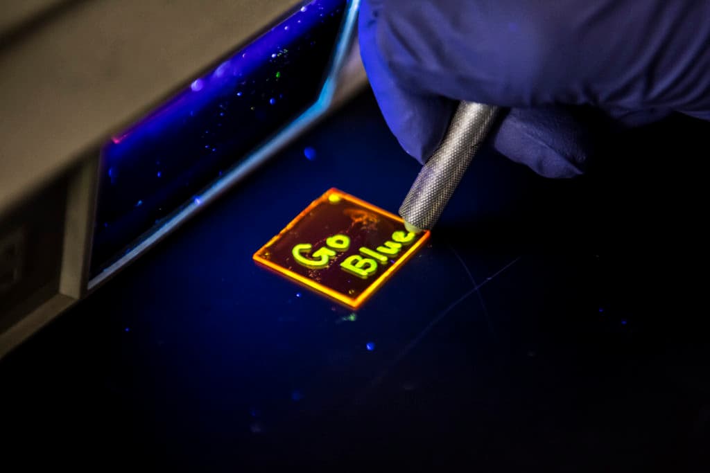 Scientist write Go Blue on microscope tray in neon yellow